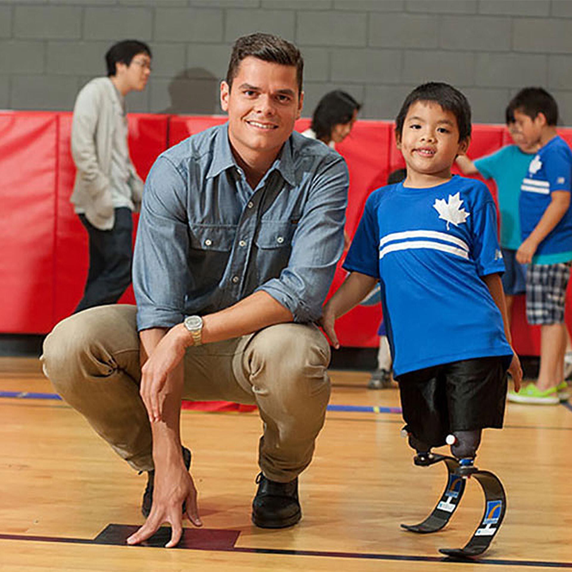 Tennis player Milos Raonic posing with kid in gym