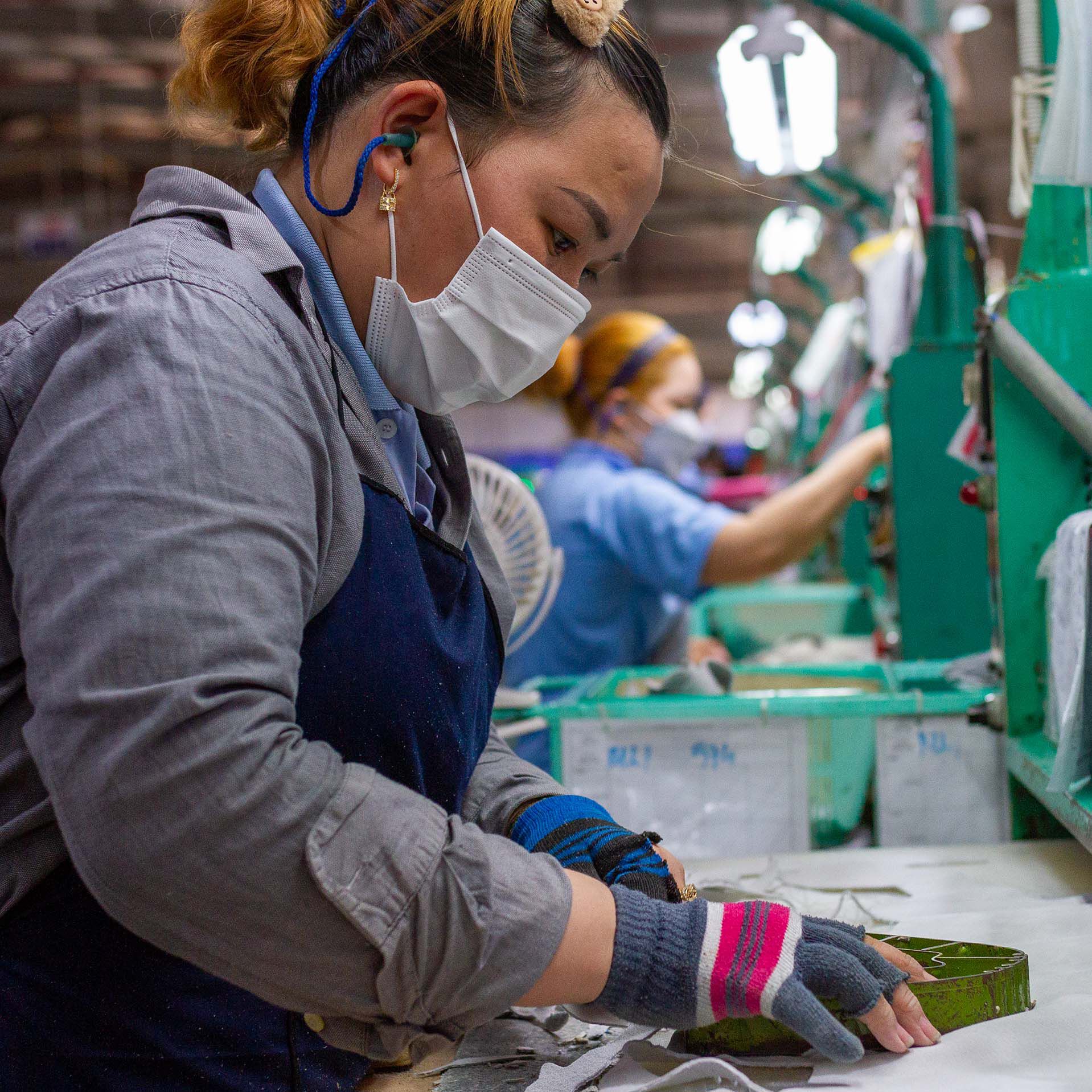 Female factory worker cutting material at work station