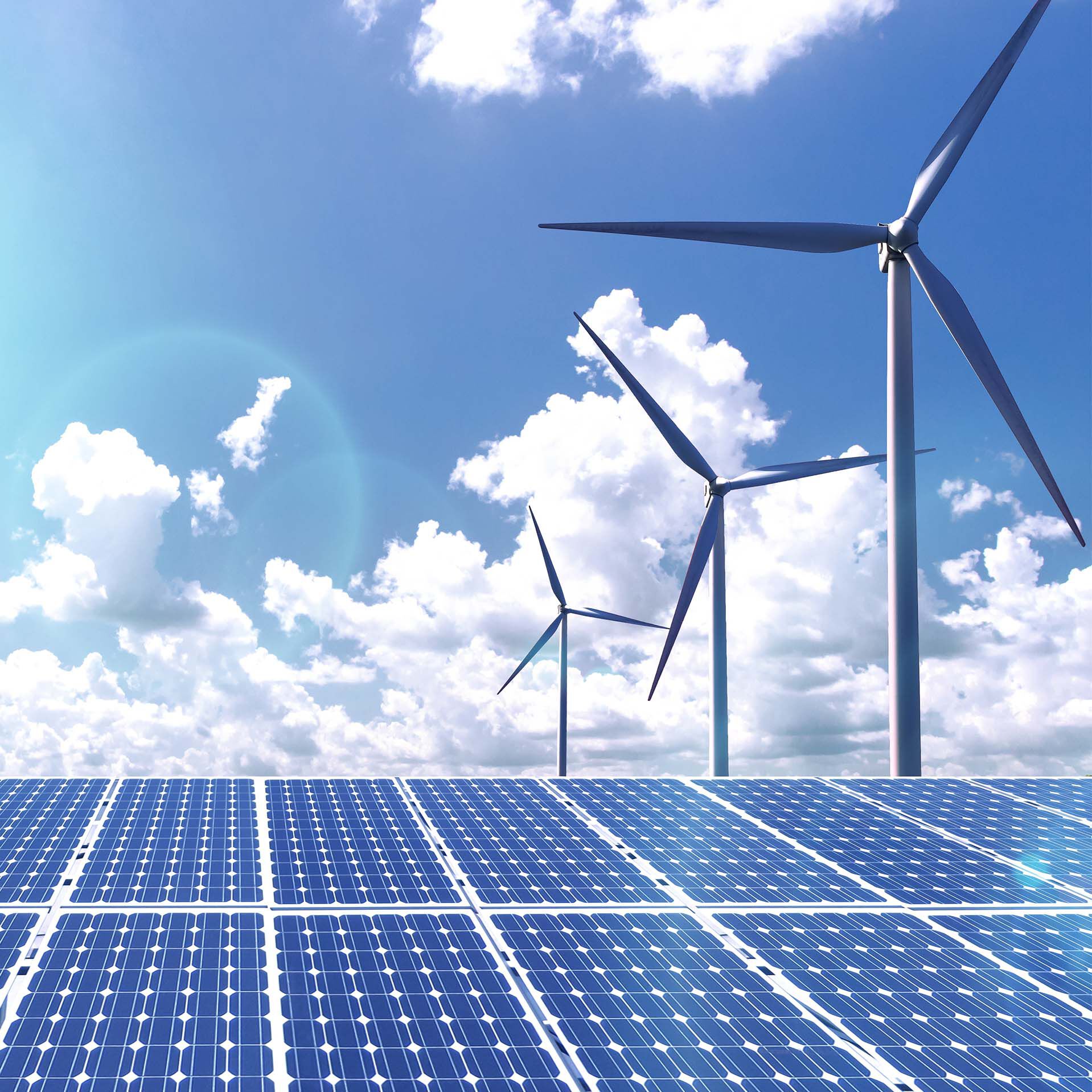 Solar panels and windmills set against a blue sky with clouds